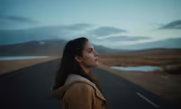 a girl with dark hair standing in the road