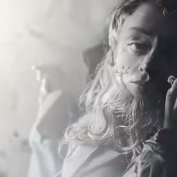 a woman is smoking a cigarette in a light haze
