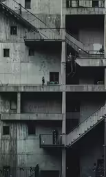 an old gray building with staircases next to a parked car