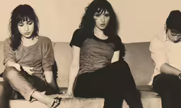 three girls sitting on top of a couch and one is reading