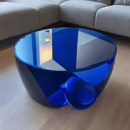 a modern blue table is sitting in front of a gray sofa