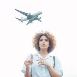 woman with red hair standing under an airplane