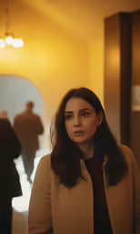a woman stands in a hallway with people standing in the background