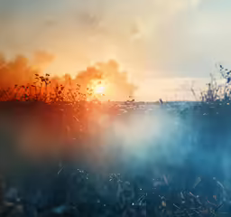 the sunset is rising over a cloud covered field