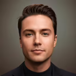 a man with a suit and tie looking into the camera