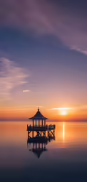 the sun sets over the horizon as people are sitting on a platform