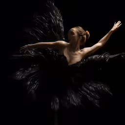 a woman dressed in black feathers standing with her arms outstretched