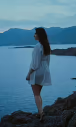 woman standing at cliff on a blue water side