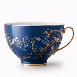 a cup on a white surface with gold designs