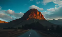 a road surrounded by mountains in the sunset