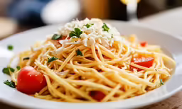 a plate of food, including spaghetti, tomato and parmesan