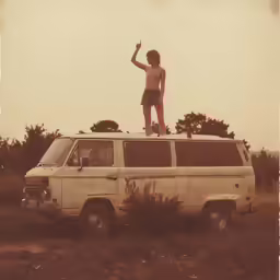 a young man stands on the roof of a van