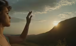 a young woman on the cliff looks into the sun