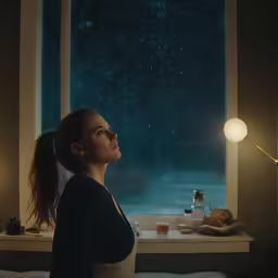 the girl looks out the window while eating breakfast