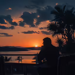 the silhouette of a man sitting at an outdoor table