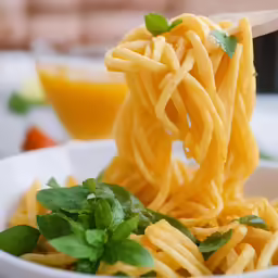 a forkful of macaroni and cheese with herbs in it