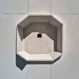 a square gray concrete object suspended on a wall