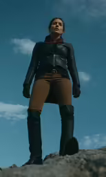 a woman standing on top of a rock looking up