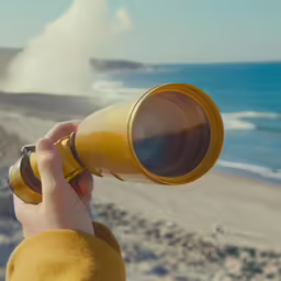 a person looking through a binoculars lens at the beach