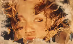 a young boy in an artistic photograph is blowing soap bubbles