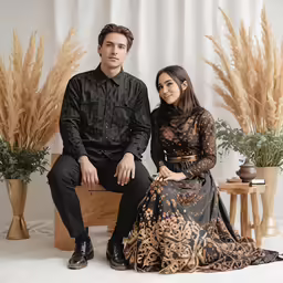 a man and a woman sitting in front of some plants