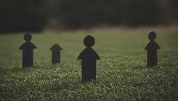 a little paper man with four other men in the grass