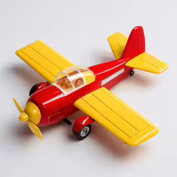 a red and yellow plane sitting on a white surface