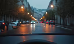 city street with streetlights on and cars in the rain