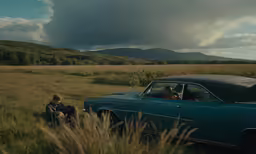 two men in an old car with clouds overhead