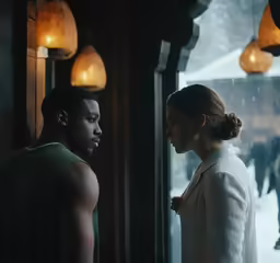 two people standing in front of a window near snow