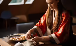 a young lady is holding the edge of a cup while pouring tea into a bowl