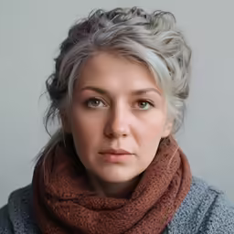 a blonde woman with light colored hair wearing a scarf and grey sweater