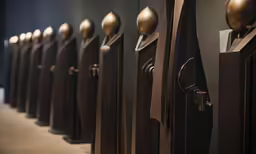 several bronze clock faces lined up against the wall