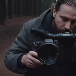 the man has long hair and a beard holding a camera