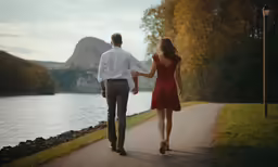 a man and woman walking down a path holding hands