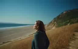 a person is looking at the ocean on a hill