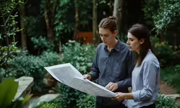 two people in the middle of a forest with a paper