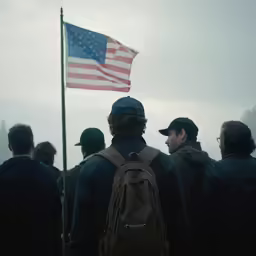 a soldier with a hat and a backpack stands by an american flag