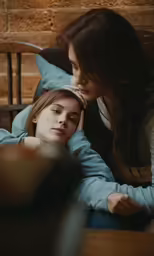 a beautiful young lady sitting next to a young girl