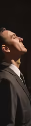 a man in a black suit looking into the sky