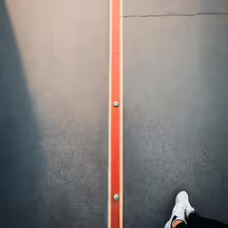feet standing next to black and white street with orange lines