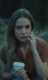 a woman sitting on the ground with a cup of coffee