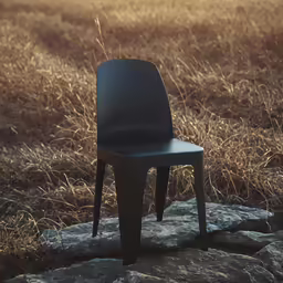 a small black chair sits on a rock next to a field