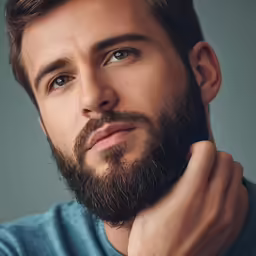 a man with a blue shirt on is holding his hand near his face