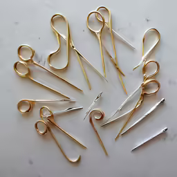pairs of gold colored metal scissors on a white surface