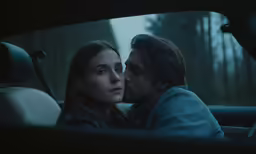 a man is sitting in the back seat of a car and kissing a woman