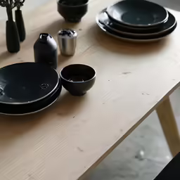 black dishes sit on a table with a wooden bench