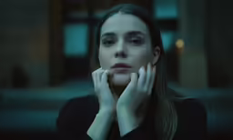 a beautiful young woman is sitting in a dark room