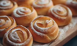 doughnuts with powdered sugar on top sitting on a cutting board