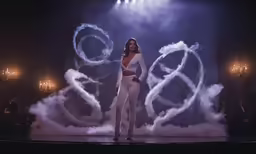 a woman is standing on stage in front of smoke